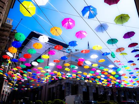 Genova, Italy - 0/29/2020: Multicolored umbrellas against the sky, street decorated. LGBT flag. Rainbow love concept. Human rights and tolerance.