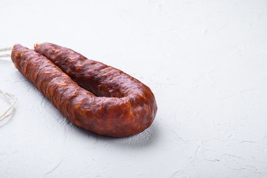 Dry cured chorizo sausage on white textured background with copy space.