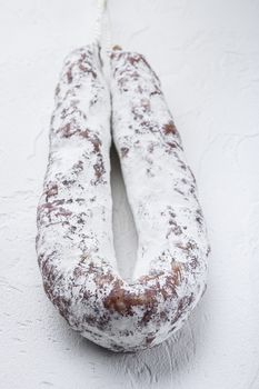 Salami sausage fuet on white textured background.