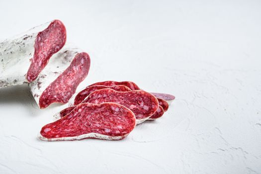 Sliced cuts of longaniza, dry cured spanish sausage on white surface with copy space.