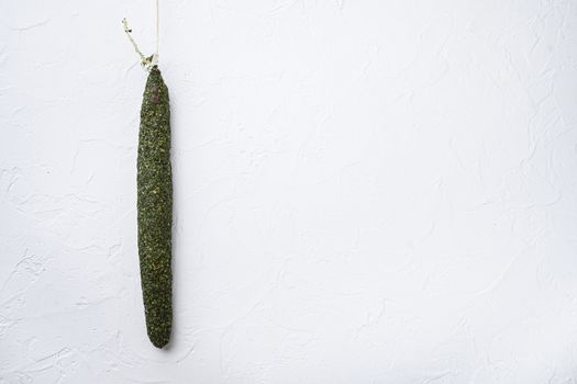 Fuet, salami sausages on white textured background with copy space.