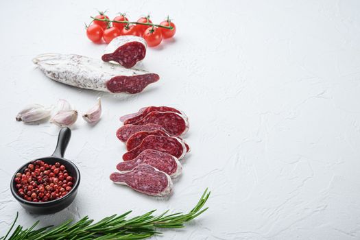 Sliced cuts of longaniza, dry cured spanish sausage with herbs and spices on white surface with copy space.
