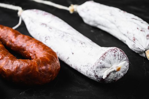Traditional spanish sausages fuet and chorizo on black surface.