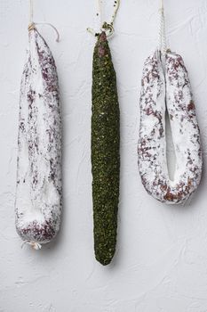 Traditional dry cured sausages meat hanging on white background.