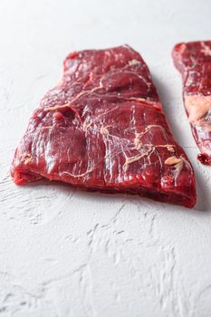 Raw Flap meat, London Broil organic meat cut side view close up over white concrete background vertical selective focus.