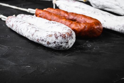 Traditional spanish sausages fuet and chorizo on black textured background with copy space.