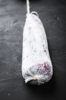 Spanish traditional longaniza sausage on black surface.