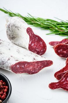 Sliced cuts of longaniza, dry cured spanish sausage with herbs and spices on white surface.