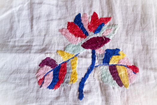 colorful flower hand made embroidered smooth decoration on white fabric , vintage folk embroidery in Belarus, second half of 19 century