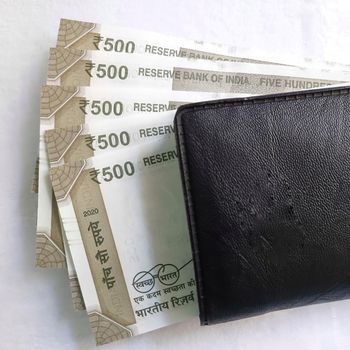 Indian new rupees currency notes arranged orderly number upwards manner with all rupee coins in white paper in wallet