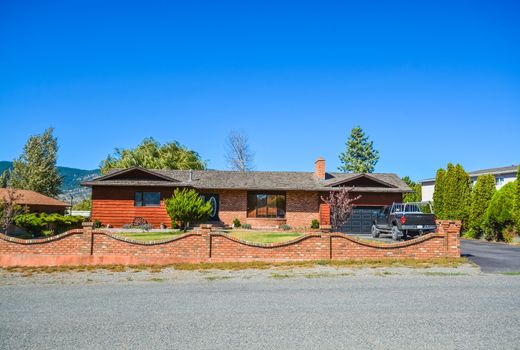 Red brick built residential house with red brick wall on front yard. Family house with black truck parked on asphalt driveway