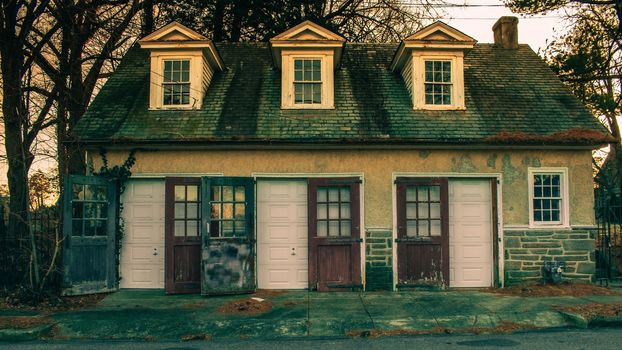 An Old-Fashioned Three Door Garage With a White Facade and Windows on Each Door