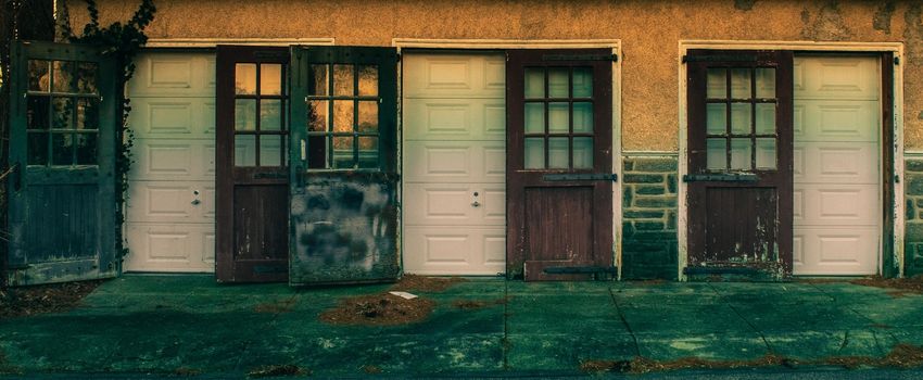 An Old-Fashioned Three Door Garage With a White Facade and Windows on Each Door