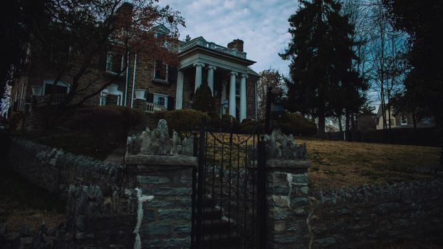 An Estate Like Building With a Large Front Yard, White Columns, and Trees Out Front