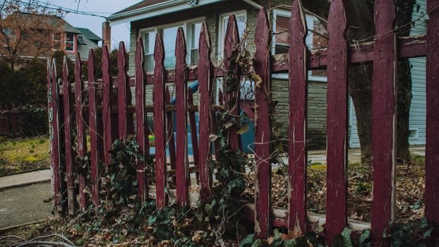 An Old and Weathered Red Wooden Fence Out Front of a House