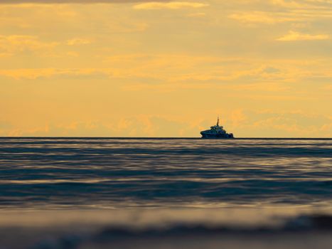 One small fishing boat heading out on the foggy ocean at dawn. Boat on the background of sunset. The Baltic Sea close up, stormy dramatic dark clouds. The Vacation, summer concept