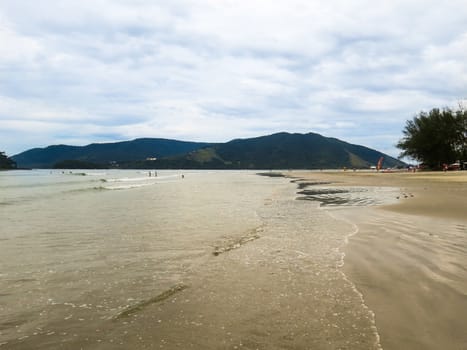 Quiet beach without waves with a wide strip of sand. At the end of the afternoon.