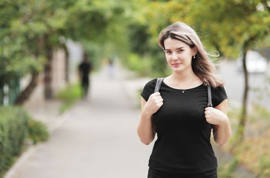 Fashion portrait of young stylish woman walking down the street, in trendy outfit, traveling with a backpack. High quality photo