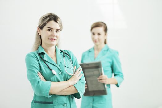 Two female doctors or nurses looking at the camera. Stethoscope phonendoscope on the neck. Holds a folder in his hands