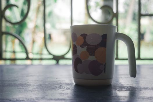 Coffee cup and window. Morning cup of coffee. Coffee cup isolated from in window sunlight in background.