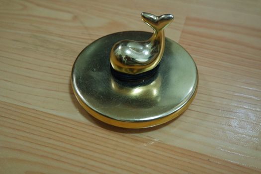 The decorative little golden pot with dolphin lid open, for room decoration. Golden pot on the vintage white background.