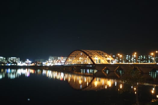 Night view of a beautiful scene of bridge over sea water in the evening time with colorful lights.