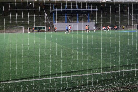 Night view of a soccer goal net under flood lights. Closeup view of goal net in a soccer playground