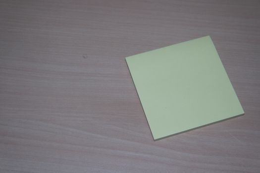 Close-up, selective focus: Yellow sticky note paper placed on a wooden table with copy space for text