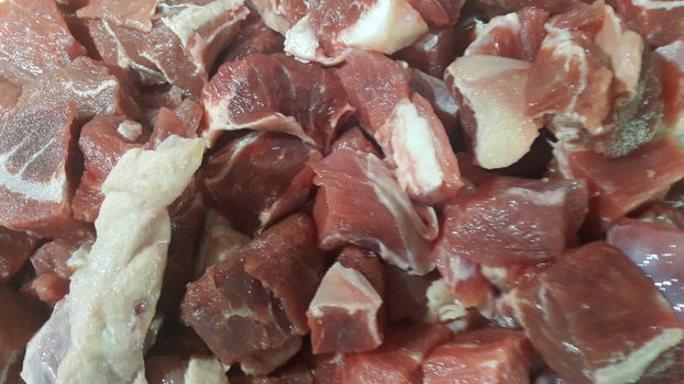 Close up view of fresh finely chopped meat cubes. Red meat small steaks with whitish meat fat.