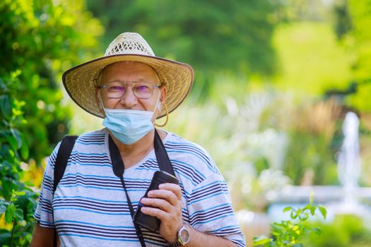 Portrait of an old man a wearing medical mask protect during coronavirus in a park