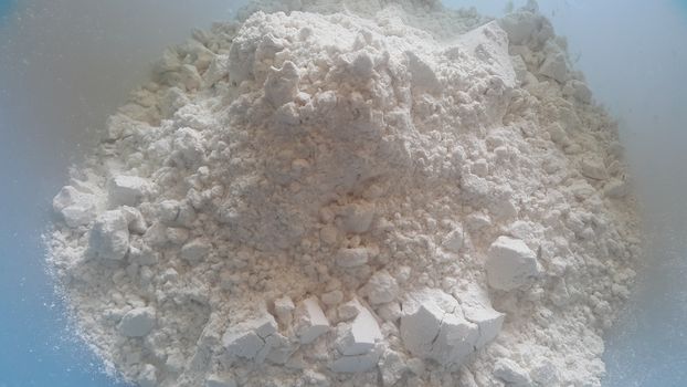 Closeup view of wheat flour heap placed in market for sale. White flour background