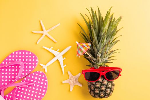 Celebrate Summer Pineapple Day Concept, Top view flat lay of funny fresh pineapple in sunglasses with model plane and starfish, in studio isolated on yellow background, Holiday summertime in tropical