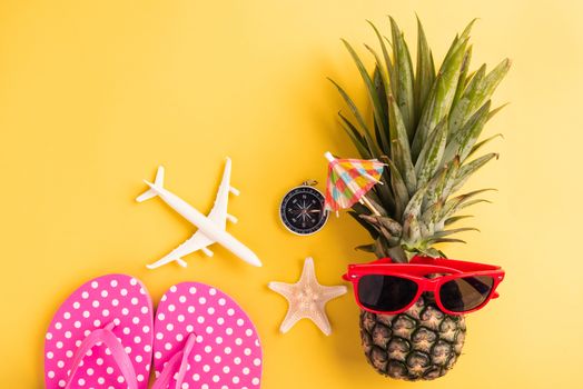 Celebrate Summer Pineapple Day Concept, Top view flat lay of funny fresh pineapple in sunglasses with model plane and starfish, in studio isolated on yellow background, Holiday summertime in tropical