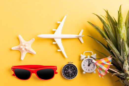 Celebrate Summer Pineapple Day Concept, Top view flat lay of funny pineapple, sunglasses, model plane, starfish and clock alarm isolated on yellow background, Holiday summertime in tropical