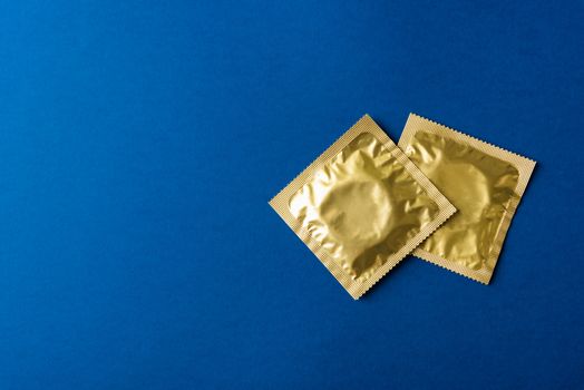 World sexual health or Aids day, Top view flat lay condom in wrapper pack, studio shot isolated on a dark blue background, Safe sex and reproductive health concept