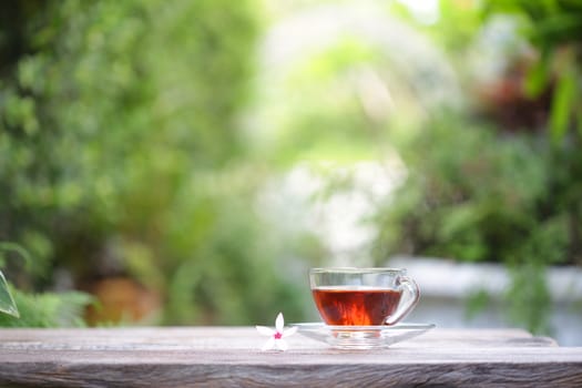 red tea in transparent glass and diary notebook with flower on wooden table