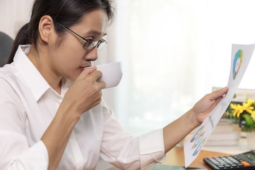 Close up Asian business women working at home analysis report chart. Business people looking workplan paper on hand.
