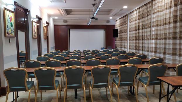 Conference Meeting Room with ceiling LED lights, Row of green Chairs, with Stage and Empty Screen for Business Meeting, Conference, Training Course, used as Template of The Elegant Design Office