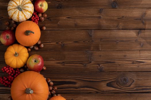 Autumn background with pumpkins, apples and nuts. Dark rustic wooden background with copy space for text