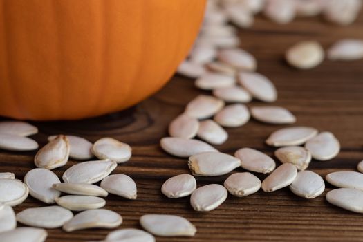 Pumpkin and pumpkin seeds on wood background close up