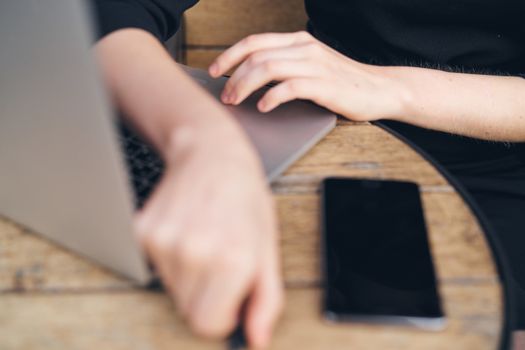 Laptop on table mobile phone female hands work cropped view of freelancer. High quality photo