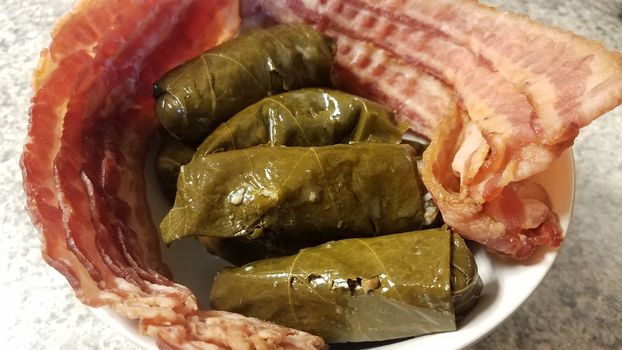 rice stuffed green grape leaves with bacon strips in bowl