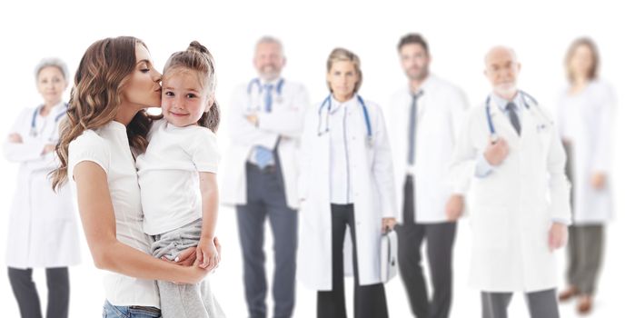 Mother kisses her daughter, team of doctors in medical clinic on background isolated on white