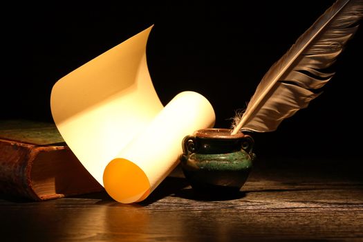 Vintage still life with old book and quill pen on dark background