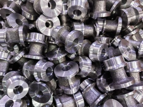 abstract close-up full frame dark industrial backdrop of forged and turned small steel spool-like parts
