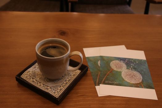 Two invitations and cup of coffee on wooden table