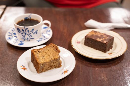 Two slices of cake and cup of coffee on wooden table