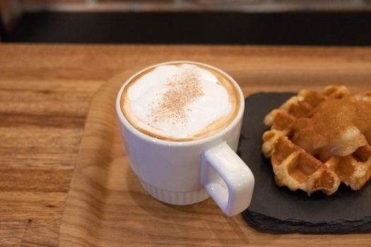 Waffle and cup of coffee on wooden table