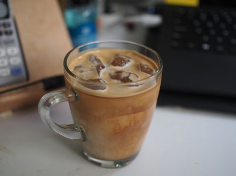 Cup of iced coffee on white table