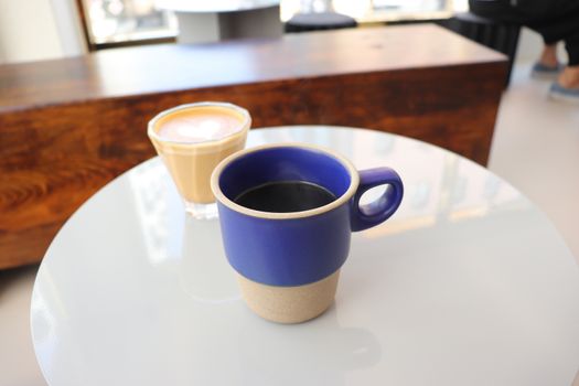 Empty cup and cup of coffee on white table